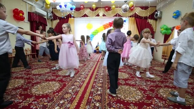 Twenty four boys and girls dance in kindergarten and two women