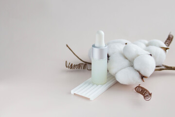 Glass bottle of facial serum and cotton branch.