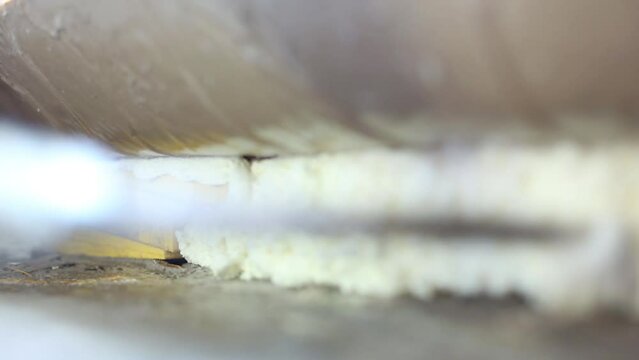 Nozzle of construction gun fills space under window frame by foam.