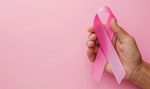 concept of hope and fight against cancer with hand gripping pink awareness ribbon , with copy space 