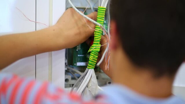 Workman packs cables in distribution box during mounting