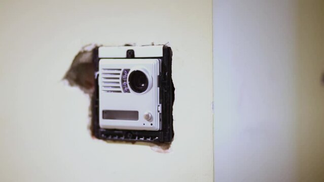 Worker mounts external part of home intercom into mounting box.
