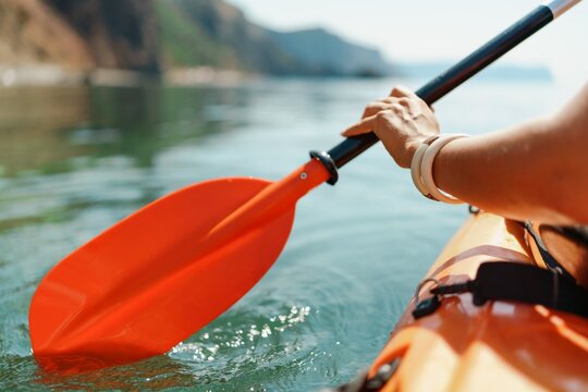 Kayak paddle sea vacation. Person paddles with orange paddle oar on kayak in sea. Leisure active lifestyle recreation activity rest tourism travel