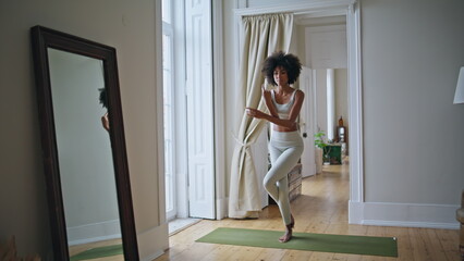 Slim model practicing yoga asana at mat. African fit woman doing namaste pose
