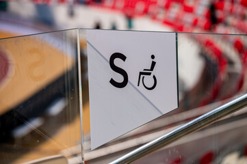 A seat for the disabled at a sports stadium. Wheelchair icon, modern stadium in the background