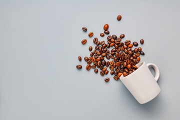 Roasted coffee beans in coffee cup on gray background. Top view.