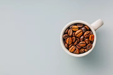 Poster Roasted coffee beans in coffee cup on gray background. Top view. © Jiri Hera