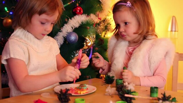 Little girl paints cone and other girl paints cookies at table