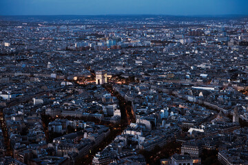 Paris city at night from above. Aerial view from Eiffel tower at blue hour. Panorama skyline after sunset. Arch of Triumph 
