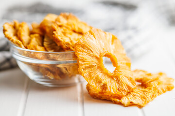 Dried pineapple rings on white table.