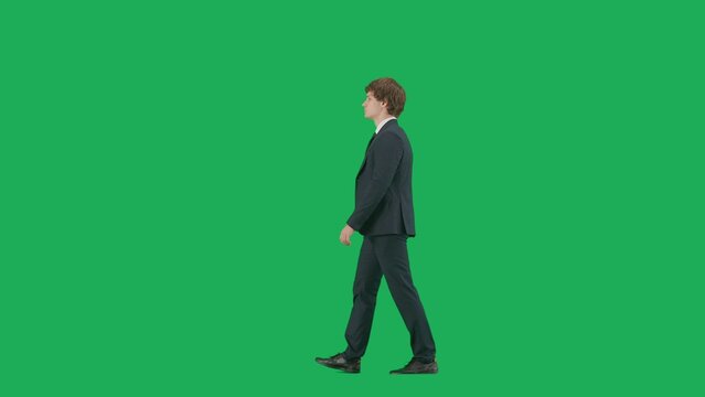 Male model in suit isolated on chroma key green screen background. Positive young businessman in blue suit walking.