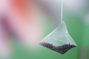 Pyramid tea bag on a gradient green and pink background. The drink of long-lived people. Photo....