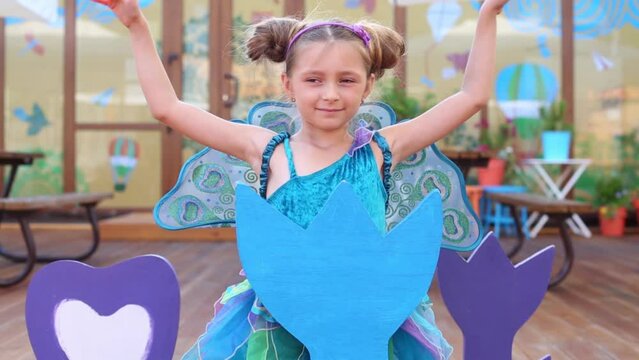 Little girl in fairy costume depict bird in children cafe 