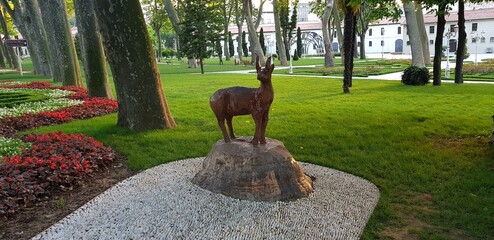 A statue of a deer in the middle of the forest looking behind