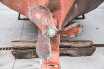 Propeller of vintage fishing boat taken out on harbor dock