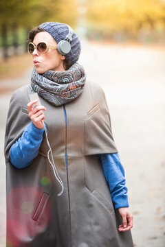 Frau im urbanen Umfeld mit Kopfh&ouml;rern, Herbst, M&uuml;nchen, Deutschland 