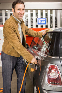 Mann l&auml;dt elektrisches Auto, M&uuml;nchen, Deutschland