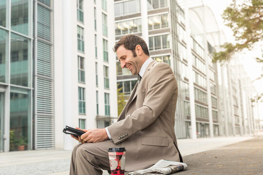 Businessmann in urbanem Umfeld arbeitet am Tablet, M&uuml;nchen, Deutschland