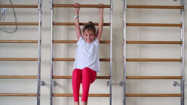 Girl does exercisers on wall bars in fitness center