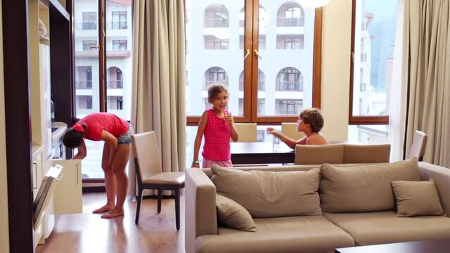 Mother and son with girl drinking water in room of hotel
