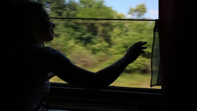 Young woman opens curtains on window in moving train