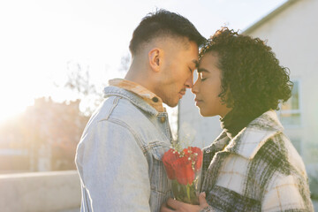 portrait of multiracial lovers with eyes closed and heads together with backlight at sunset and a...
