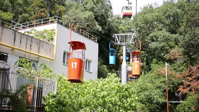 Colored funicular open wagons move near house among trees 