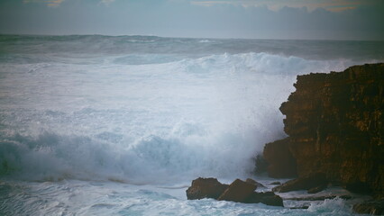 Dangerous waves hitting cliff in slow motion. Dramatic storm sea breaking rocky