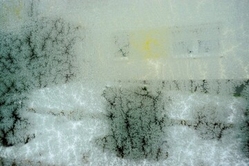 Abstraktes Motiv mit feuchter Glasscheibe und Eismuster vor Schneebedeckter Gartenlandschaft mit...