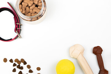 Top view of things for a dog: tennis ball, collar, dry food, jar of treats, bone on a white background. Life with dog concept