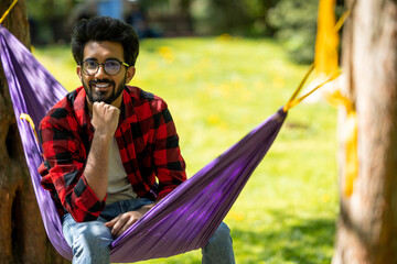 Young hindu man sitting in hammock in the park