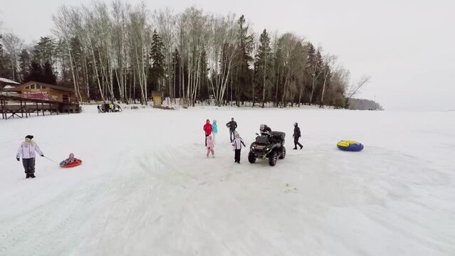 People with kids stand near quadro bike at winter cloudy day
