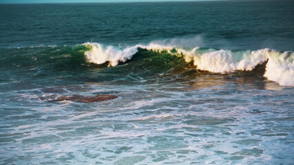 White sea waves rolling seashore on sunny day. Slow motion ocean swelling break