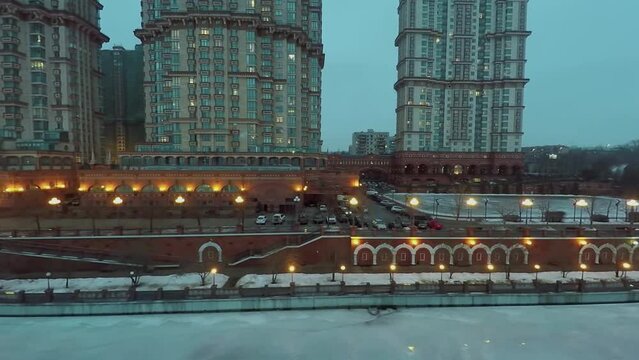 Residential complex on quay of icy river at winter evening
