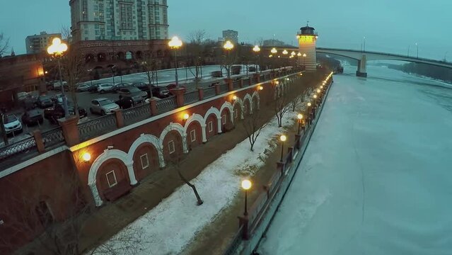 Small lighthouse on quay with illumination near residential house