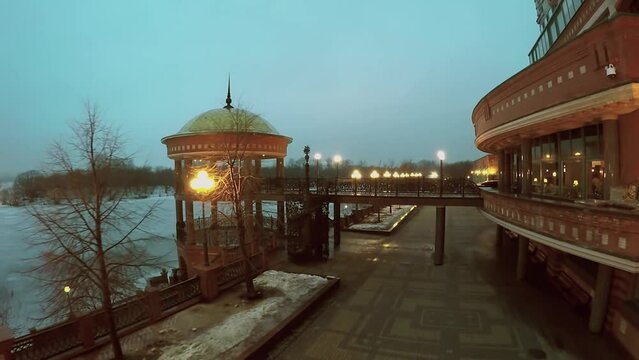 Quay with bridge to rotunda near dwelling house and icy river