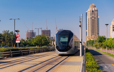 Dubai cityscape, modern metro railway with skyscrapers, sunset. Traffic train and building with...
