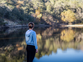Fototapeta premium Woman Overlooking a Serene Lake in a Wooded Area
