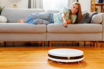 Young Woman Using Remote Control with Robotic Vacuum