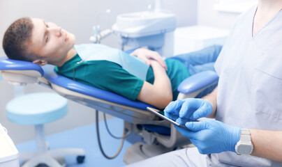 Closeup Dentist use digital tablet, background client patient man, banner technology in modern dental clinic