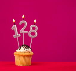 Birthday cupcake with candle number 128 - Rhodamine Red foamy background