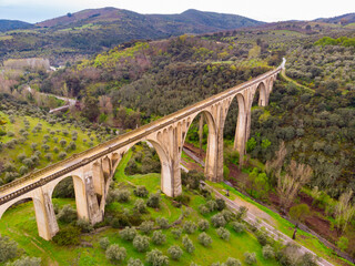 View of grand structure of arched viaduct located in picturesque area near Spanish township of...