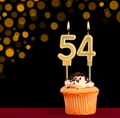Number 54 birthday candle - Cupcake on black background with out of focus lights