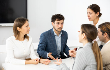 Emotional language teacher telling interesting stories to adult attentive students during class...