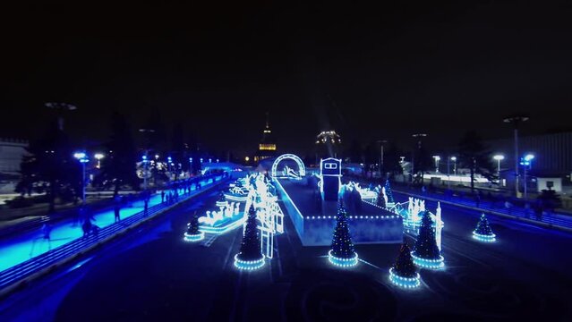 People slide by skating rink with illuminated adornments 