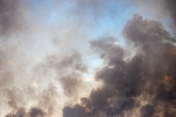 texture of black smoke against the sky during spring fires of dead wood, in the backlight of the sun