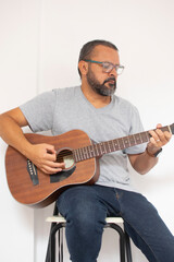 Aesthetic photo of an attractive, bearded hipster playing acoustic guitar outdoors at sunset.  acoustic guitar. Teacher.