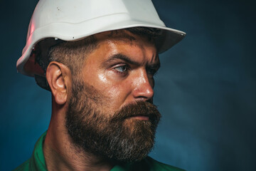 Closeup portrait of male builder in construction helmet looking to side. Mechanical or industrial worker in hard hat looks away. Serious bearded man in protective hardhat. Business, building concept.