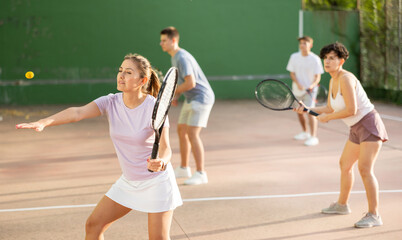 Sporty young Argentinian woman playing popular team match of frontenis at open-air fronton on...