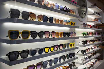 Display rack full of sunglasses. Fashionable sunglasses on the shop shelf - obrazy, fototapety, plakaty